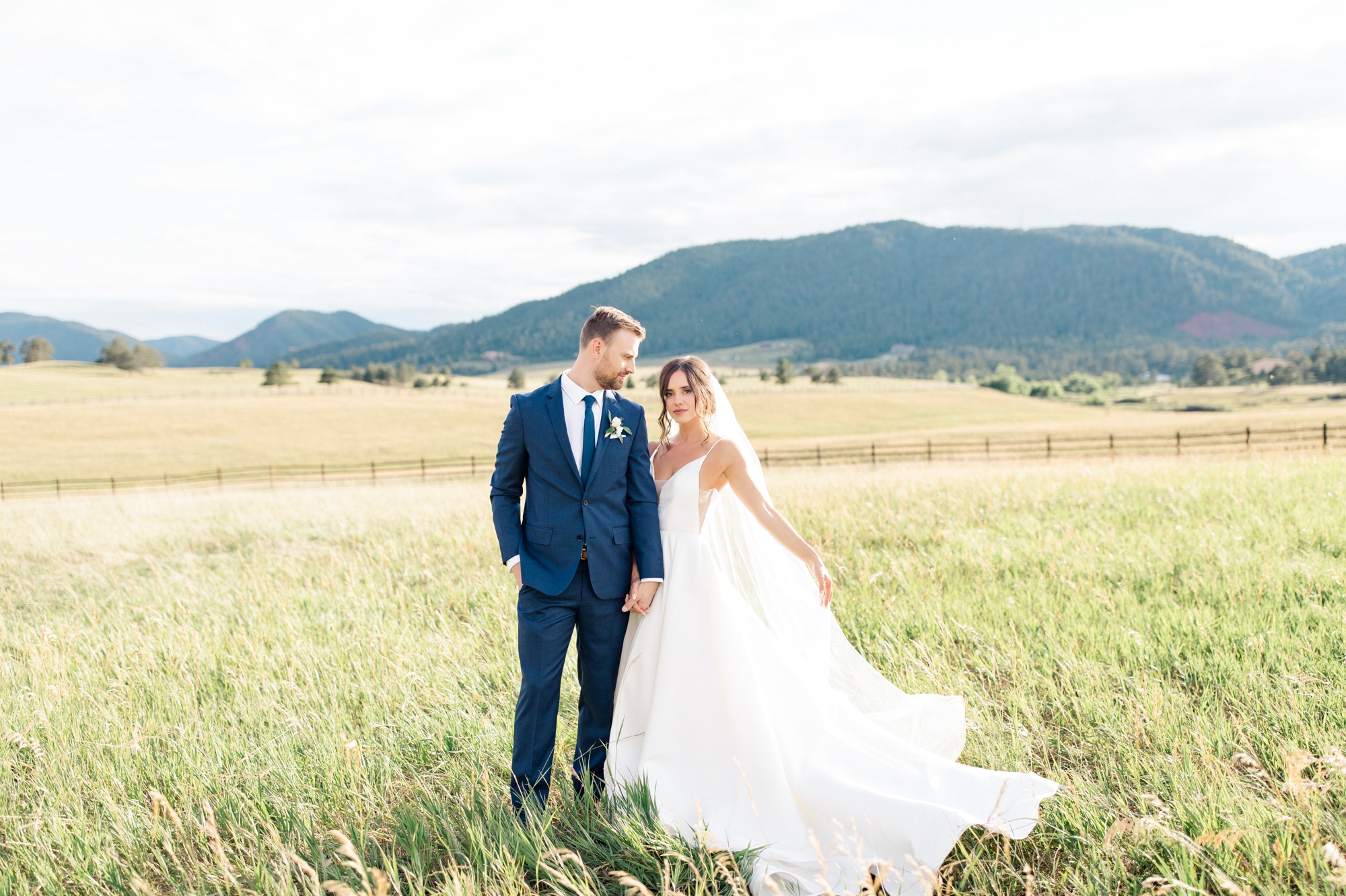 Spruce Mountain Ranch Summer Wedding, Couple in green field with Mountain View