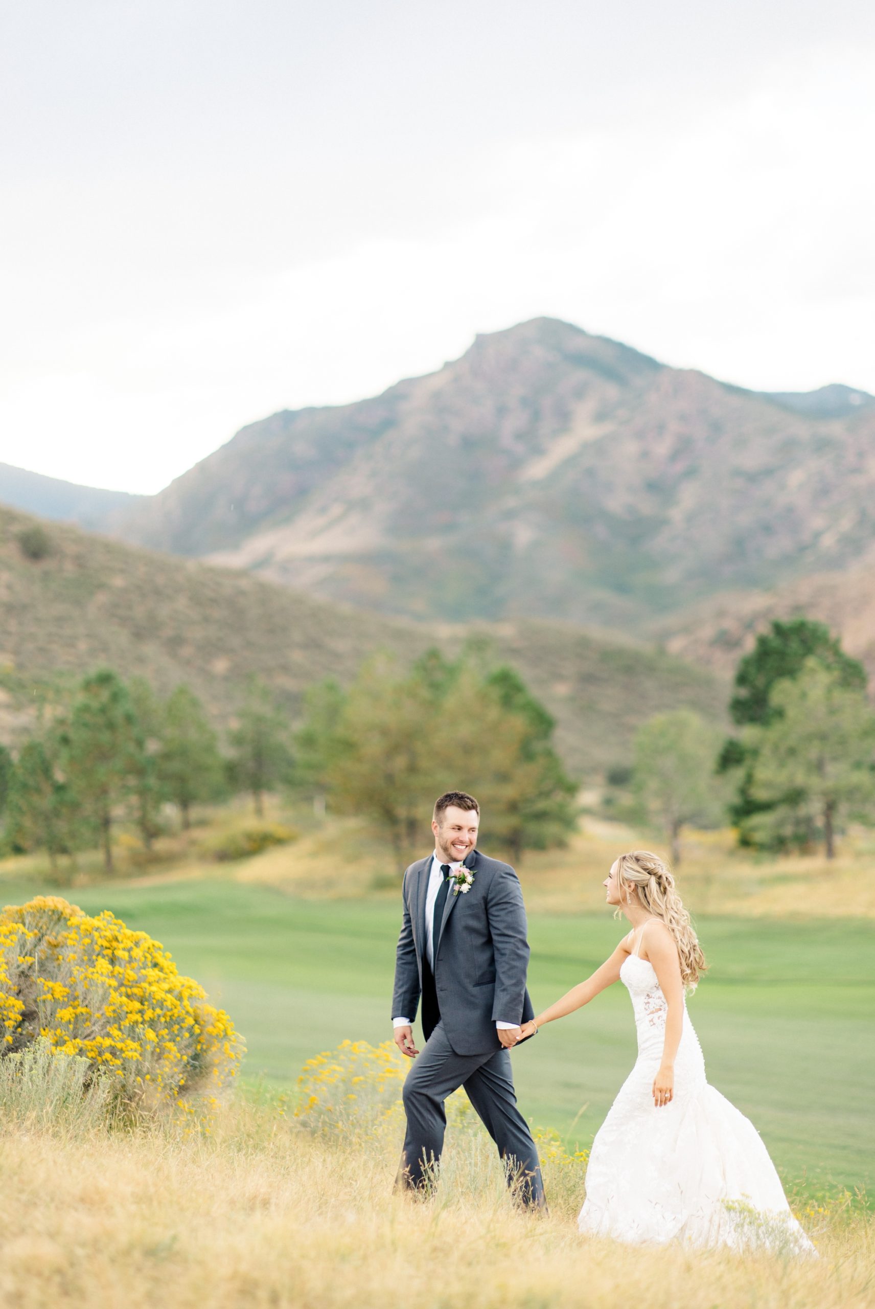 Bride and groom walking at Ravenna Golf club wedding with Mountain View behind them