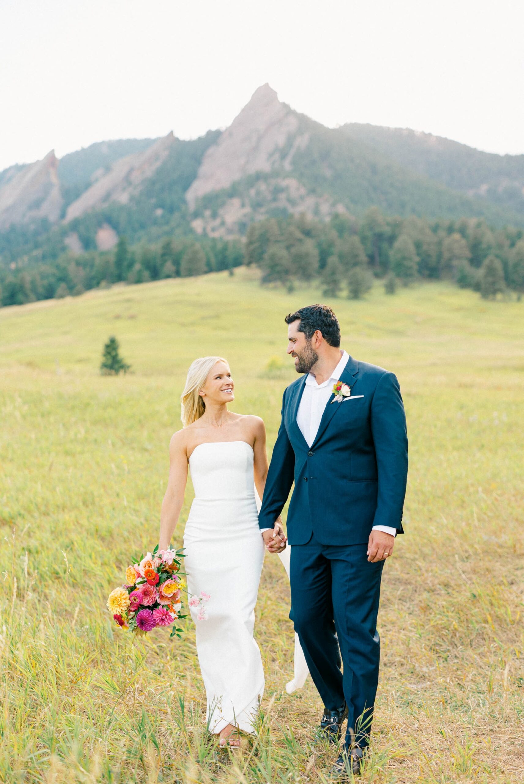 Vibrant photo of a wedding couple walking through a green mountain field in Boulder, Colorado