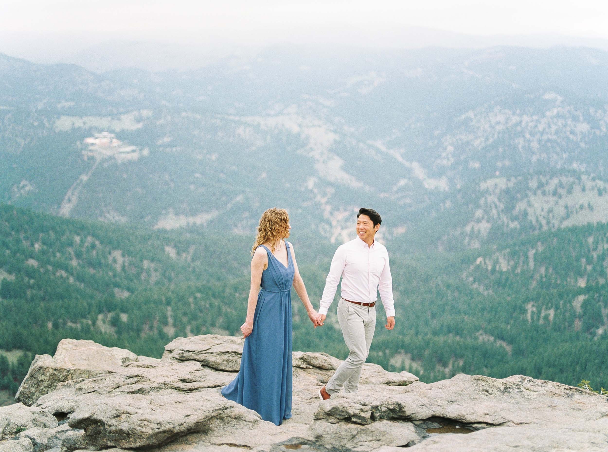 Bright image of couple walking on rocky mountain overlook in Colorado mountains